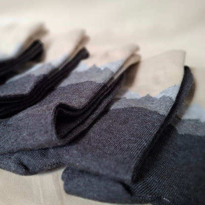 Stack of gray socks with mountain pattern on a beige surface.