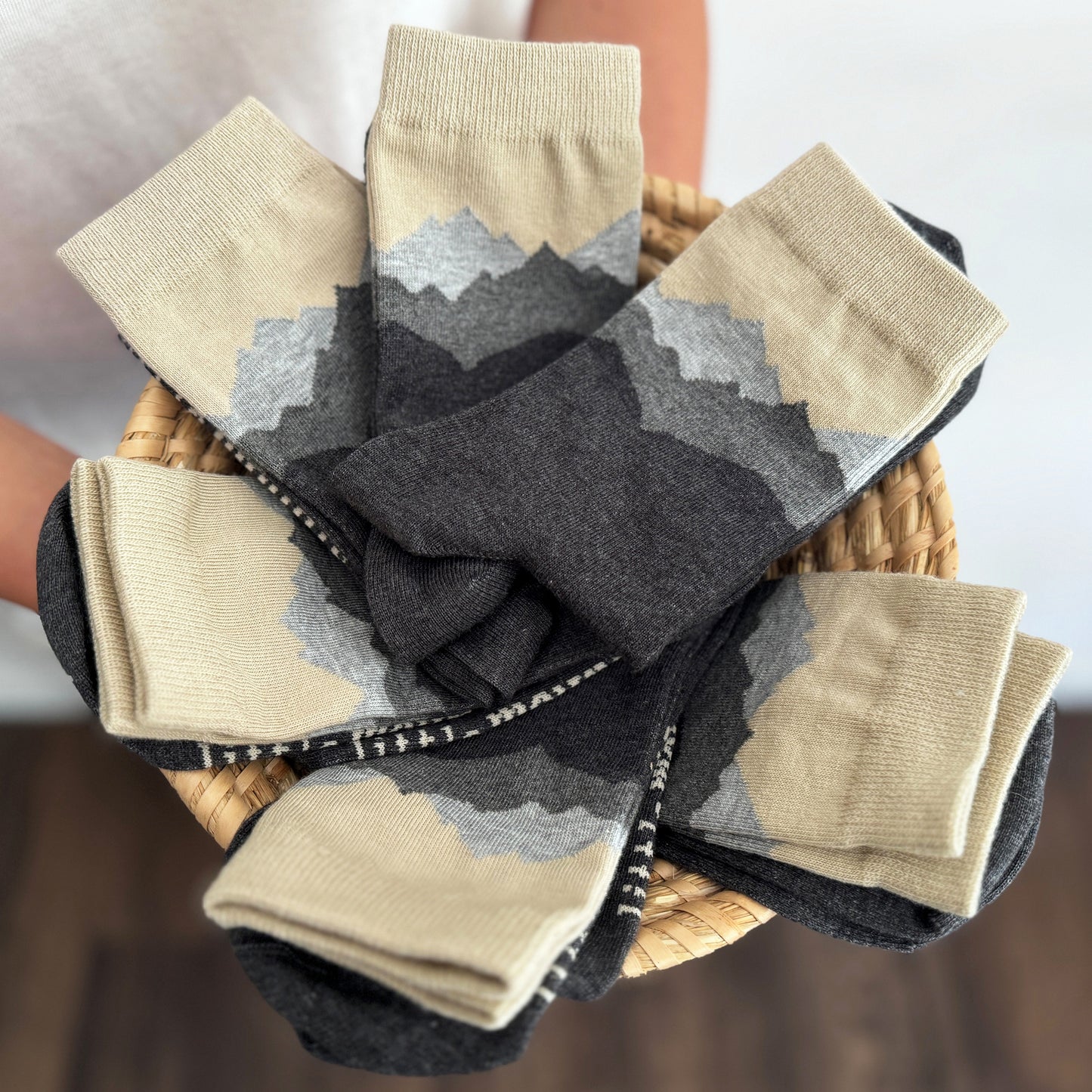Basket of patterned mountain themed socks in beige and gray.
