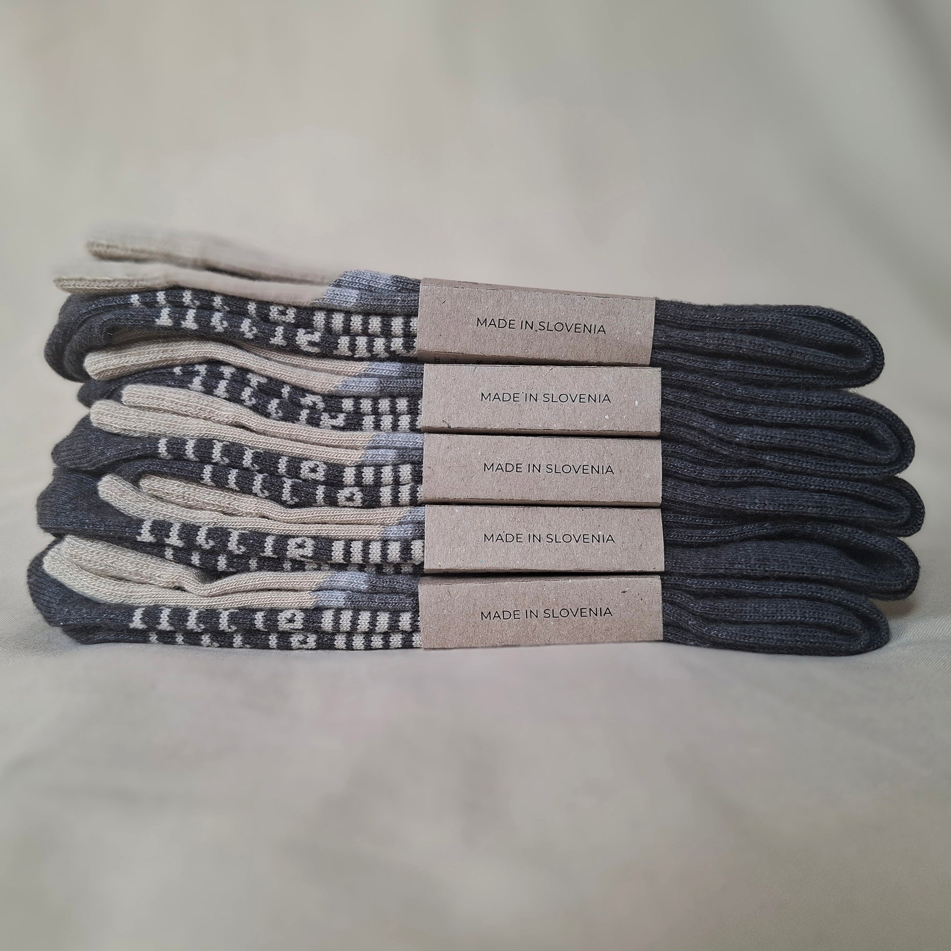 Stack of socks with 'Made in Slovenia' labels on a light gray background.